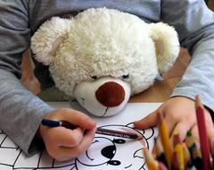 child with teddy bear paints pictures