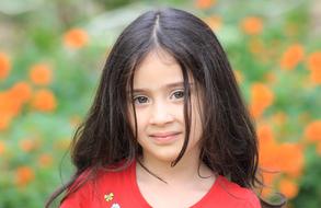 portrait of a little girl with long black hair on a blurred background