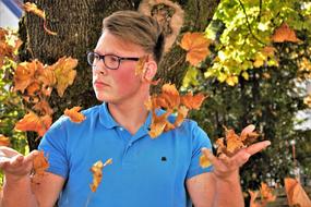 young man posing among autumn leaves