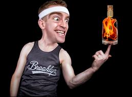 Man with the white headband, and bottle with the fire, on the finger, at black background