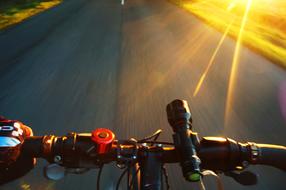 View of the person, cycling on the road, in colorful sunlight