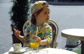 child drinks juice in a cafe