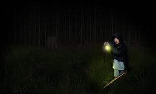 image of a young man with a lantern in a dark forest