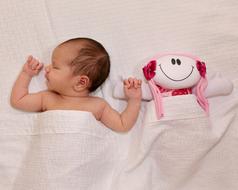 newborn with a doll on the bed