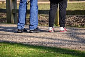 legs of a man and a woman standing by the fence