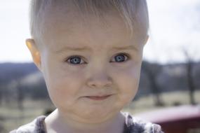 Portrait of the cute, blonde child, with the blue eyes, outdoors