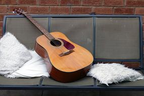 Guitar on bench at brick wall