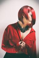 Profile portrait of the girl, with red and black hair and necklace, in light