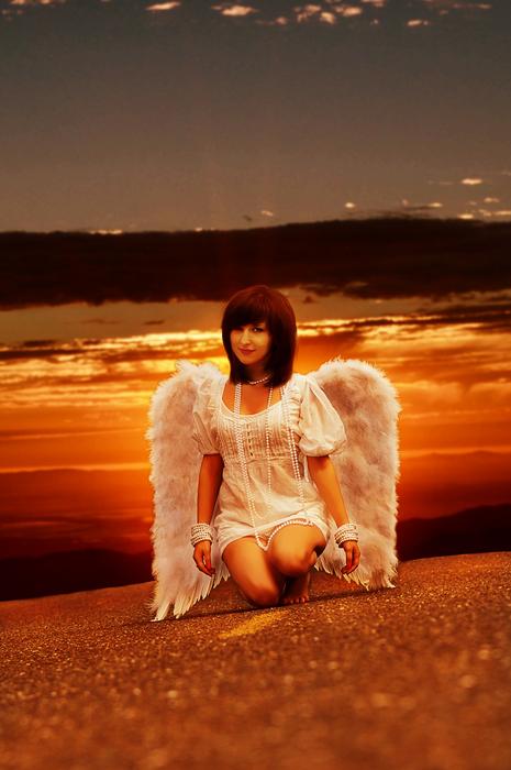 girl with white wings against the background of an orange sunset
