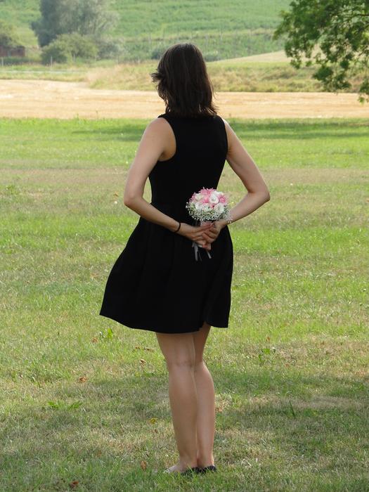 Girl in black Dress holding bouquet at her back