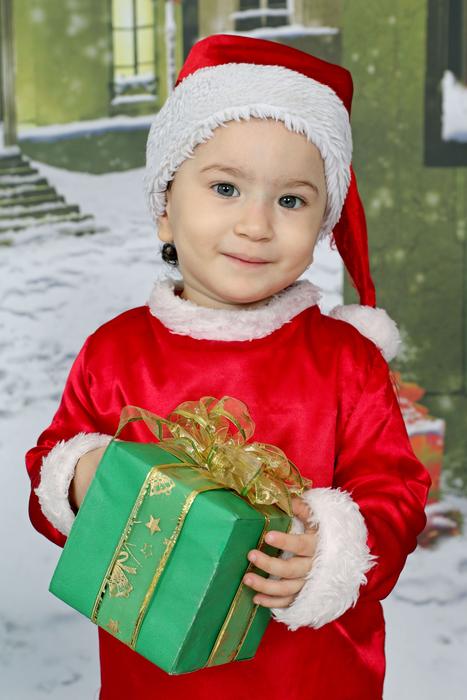 little boy dressed as santa claus with a gift