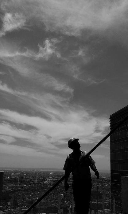 Silhouette of a person, on the construction, near the field, under the cloudy sky