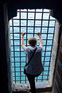 man on the window with a grid and the sea