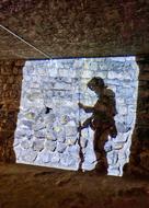 shadow of a soldier with a weapon on a brick wall