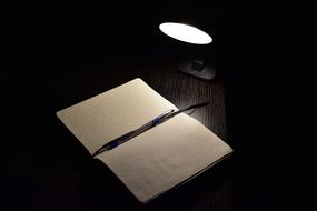 open notebook, pen, table lamp, darkness