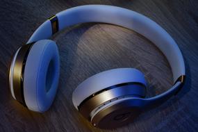 White and gold Beats headphones on the wooden surface