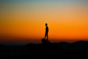 silhouette of Boy at top of rock on Golden Hour