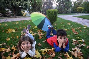 Children, laying on the green field with the colorful leaves, in Kastamonu, Turkey, in autumn