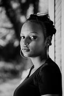 Black and white photo with the portrait of the beautiful girl with earrings, near the building