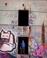 Man stands in doorway of grunge wall with graffiti