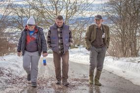 Friends, tree men walking on road at winter