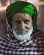 an elderly man in a green headscarf