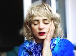 portrait of Blonde Girl with red lips holding hand at cheek