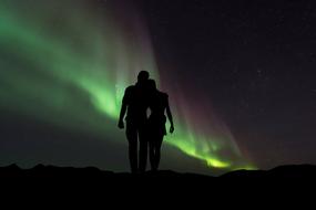 silhouette of a couple on the background of the northern lights