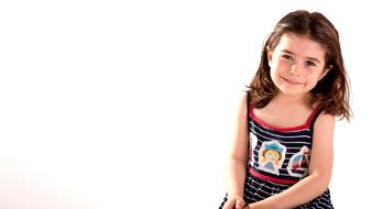 little girl with curly hair in a sundress on a white background