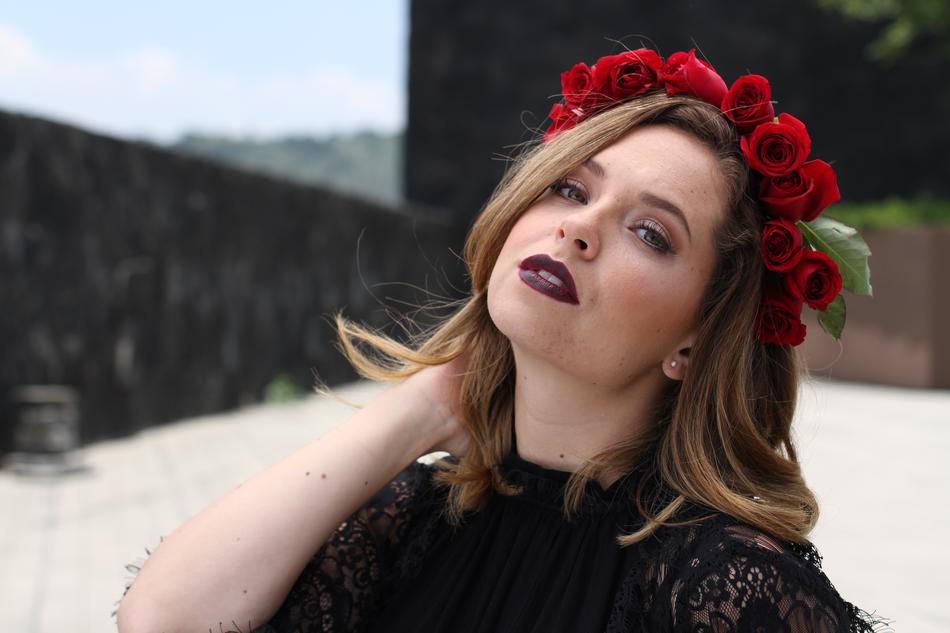 Portrait of the woman with make-up and beautiful red roses with green leaves, outdoors