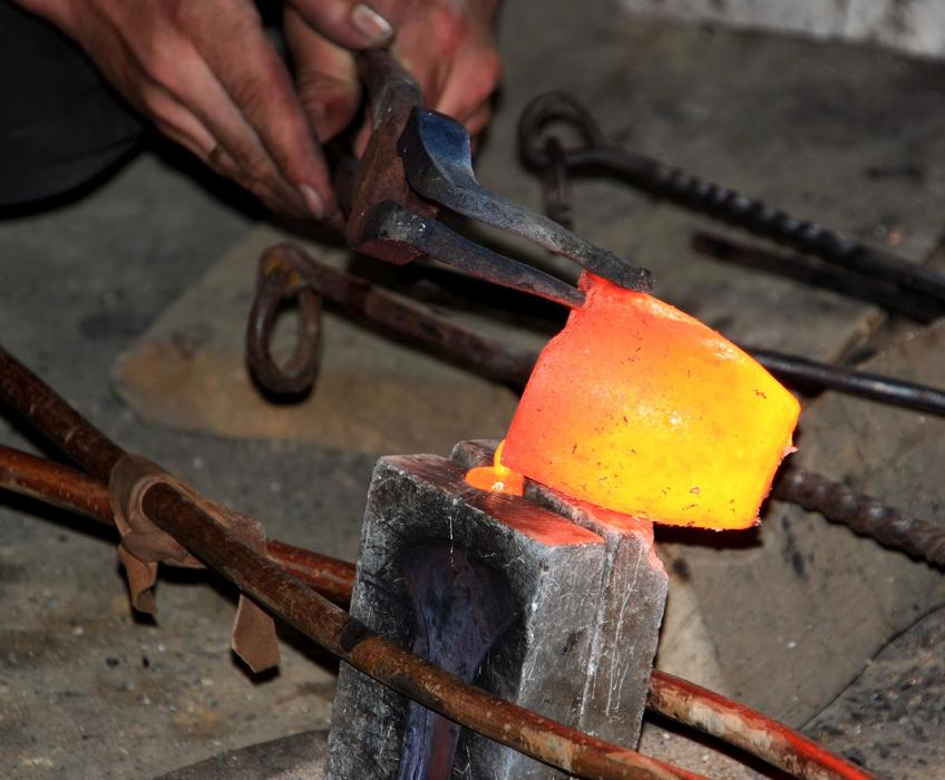 Person holding hot bronze cast with the tool