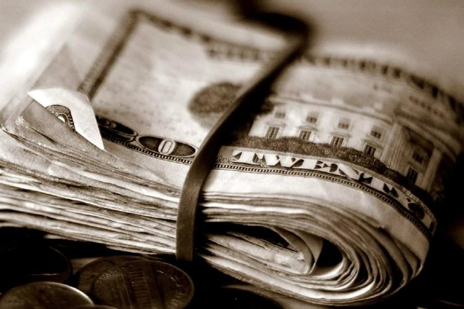 Retro photo with the close-up of the roll of banknotes in rubber