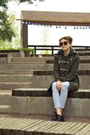 Girl with glasses sitting in the beautiful park in autumn