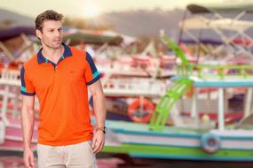 photo of a man in an orange t-shirt in the sea harbor