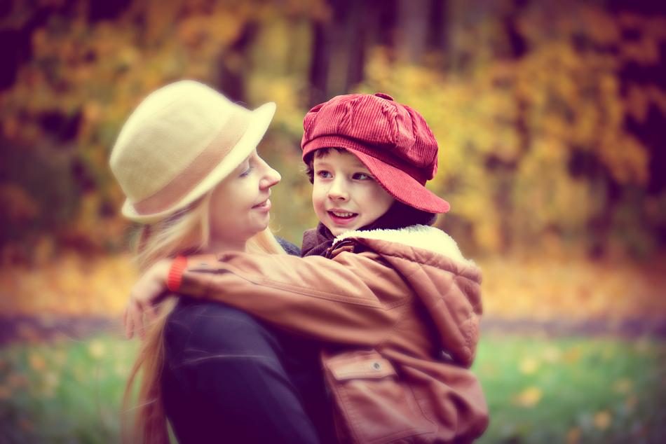 Woman with the child in hats, among the colorful plants in beautiful autumn