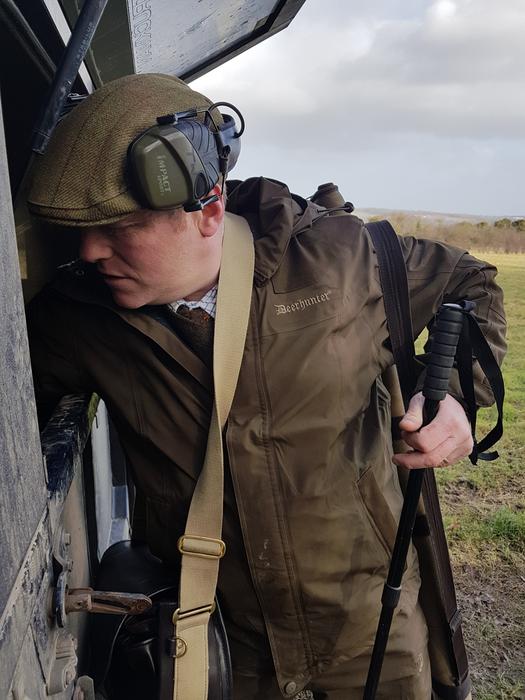 adult huntsman with a rifle near the building