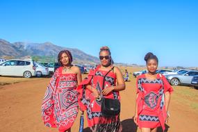 People in colorful clothing, among the cars, near the mountains, under the blue sky