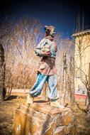 Colorful statue of man, among the plants, under the blue sky