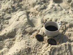 Coffee And sunglasses on sand