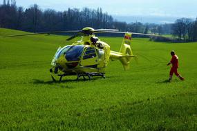 Person near the bright helicopter, among the beautiful lawn with green grass, among the trees