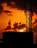 Landscape with the construction with silhouettes, at beautiful, orange sunset with clouds