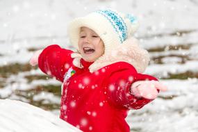 Cute child playing with snow, among the beautiful snowfall in the winter