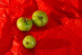 Three green fruits on a red background