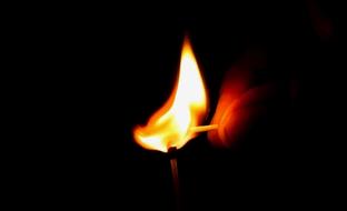 photo of two burning matches in the dark