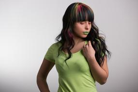 Woman with colorful hair and green lips, posing with closed eyes