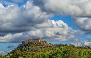 yellow building on top of a hill against a background of clouds