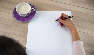 girl writes on a paper with coffee