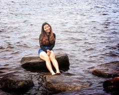 a happy girl sitting on a rock