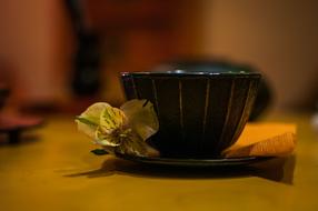 a black mug with a yellow flower on the table