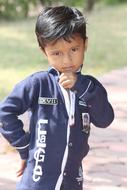 Portrait of the child boy on the path in light, near the plants